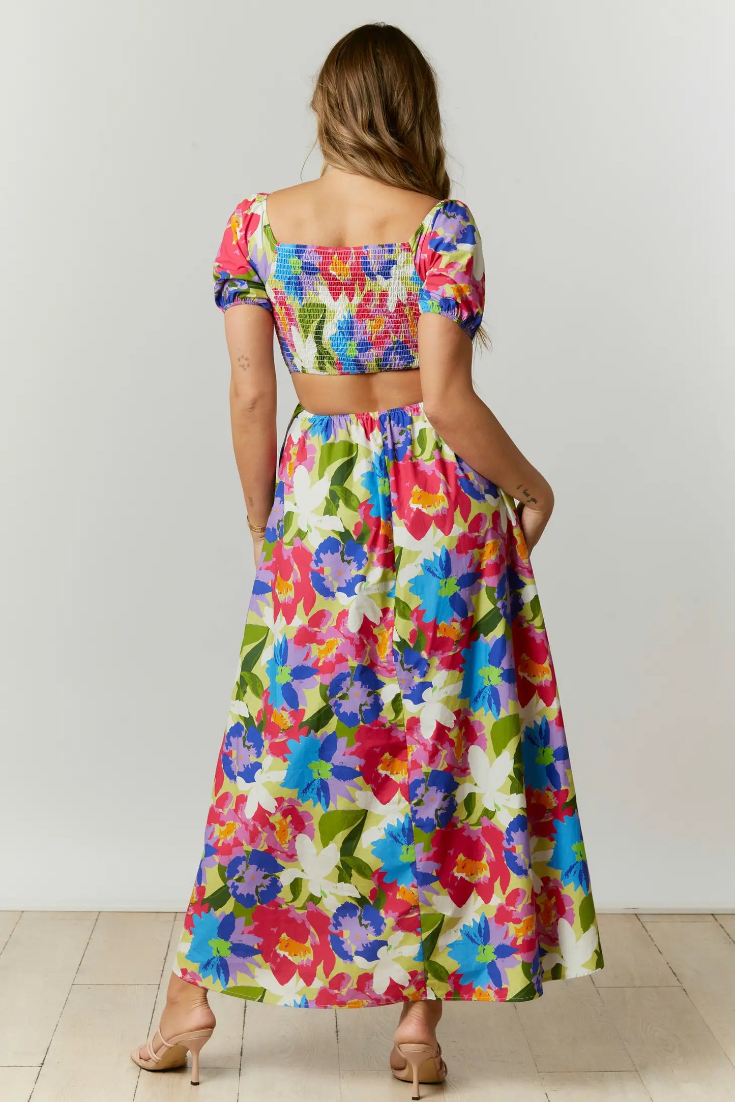 This abstract floral print maxi dress features a cut-out back with a square neckline and short puff sleeves. The dress is composed with a smocked bodice.