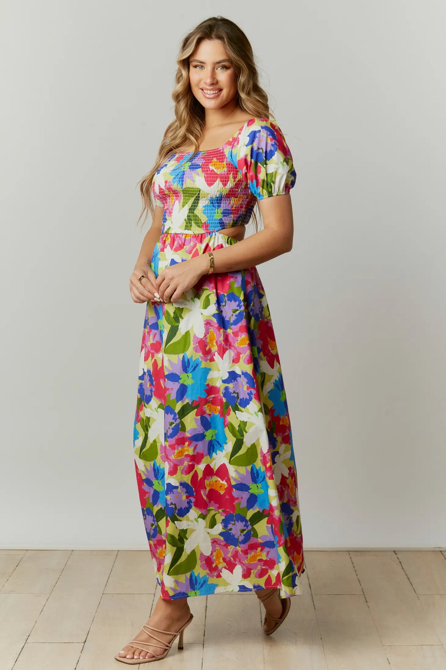 This abstract floral print maxi dress features a cut-out back with a square neckline and short puff sleeves. The dress is composed with a smocked bodice.