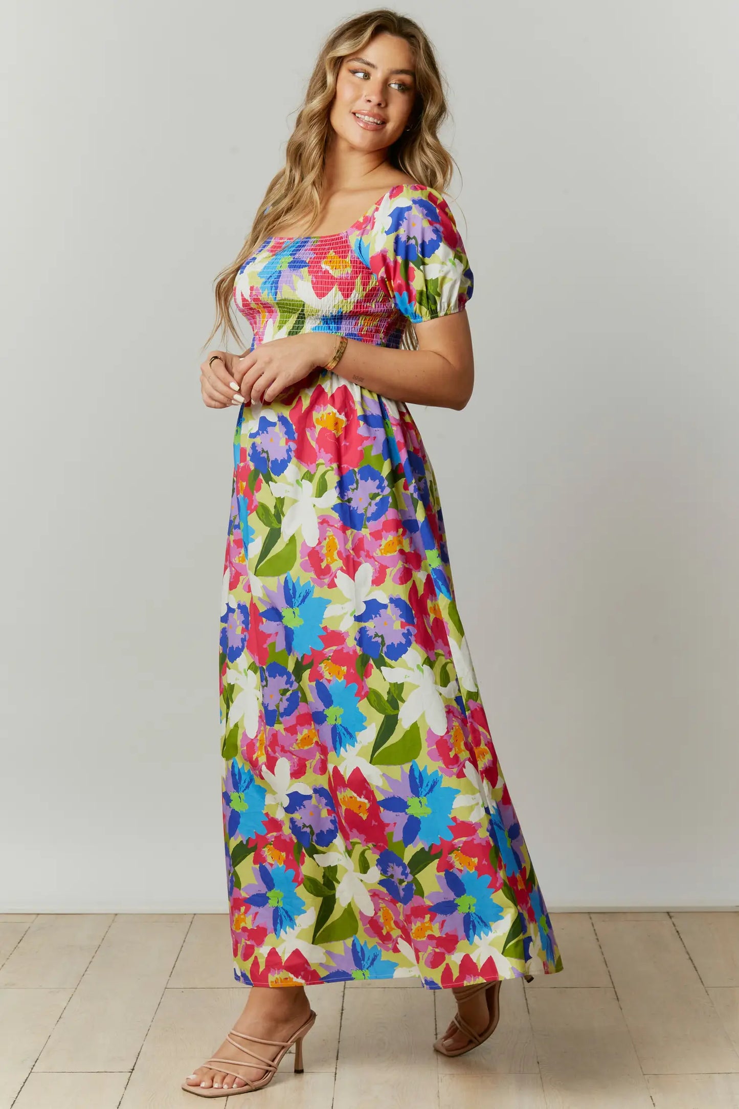 This abstract floral print maxi dress features a cut-out back with a square neckline and short puff sleeves. The dress is composed with a smocked bodice.
