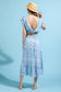 A model is wearing a blue and white skirt set. The top has a crop top and the skirt is midi length.