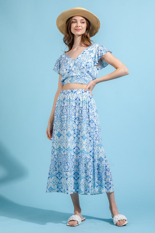 A model is wearing a blue and white skirt set. The top has a crop top and the skirt is midi length.