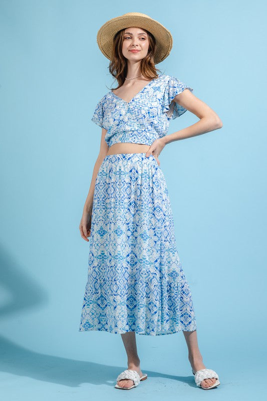 A model is wearing a blue and white skirt set. The top has a crop top and the skirt is midi length.