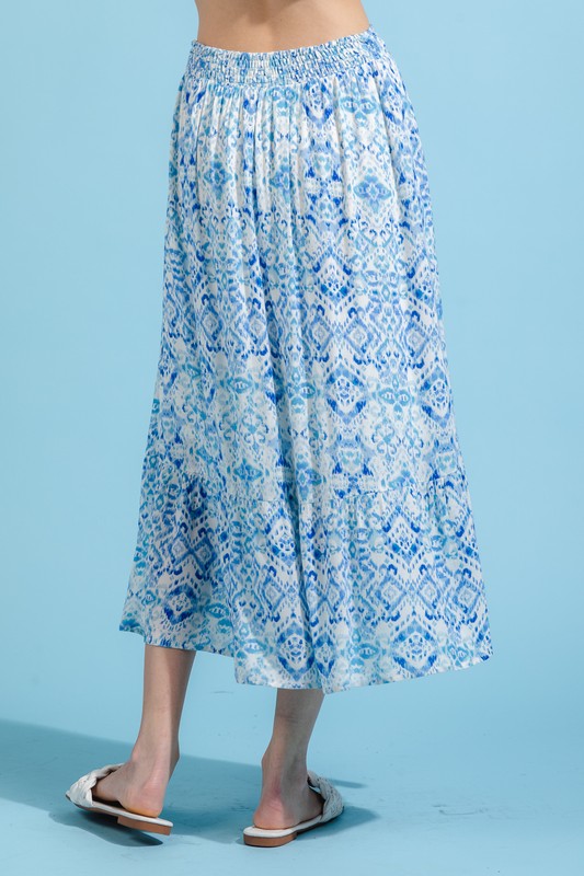 A model is wearing a blue and white skirt set. The top has a crop top and the skirt is midi length. 