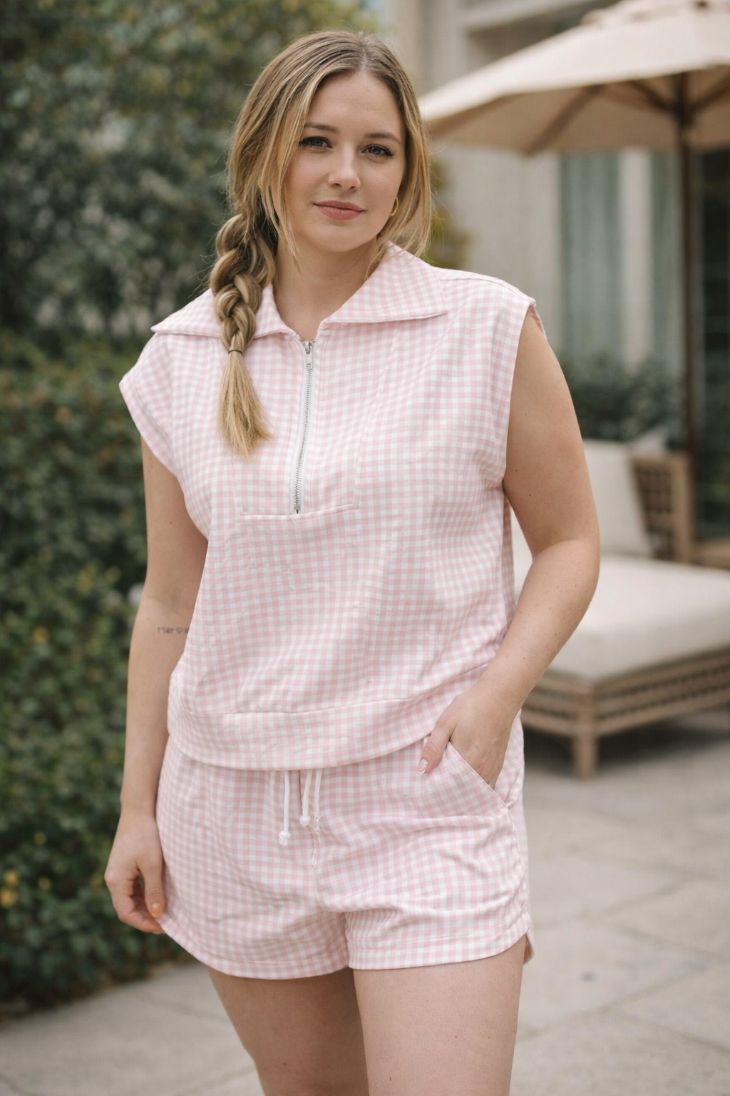 Woman wearing a pink checkered outfit standing outdoors.