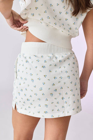 White floral skirt worn by a person on a light gray background
