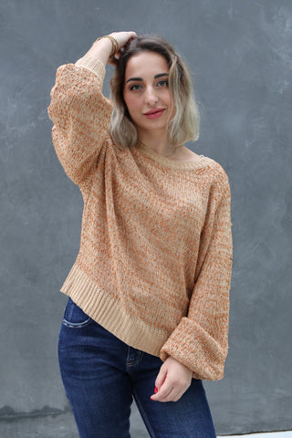 Woman wearing a beige sweater and blue jeans against a gray background