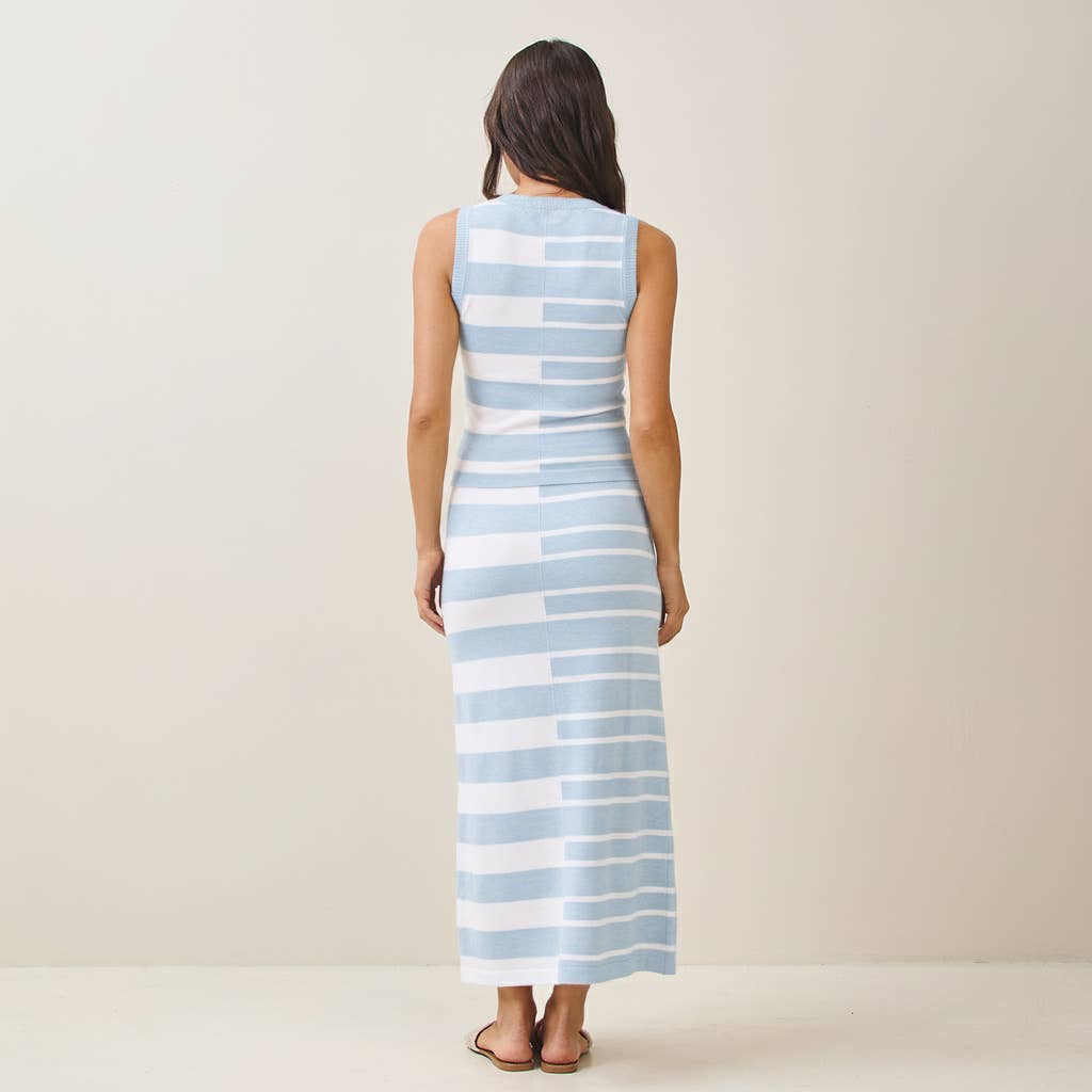 Woman wearing a long blue and white striped dress on a plain background