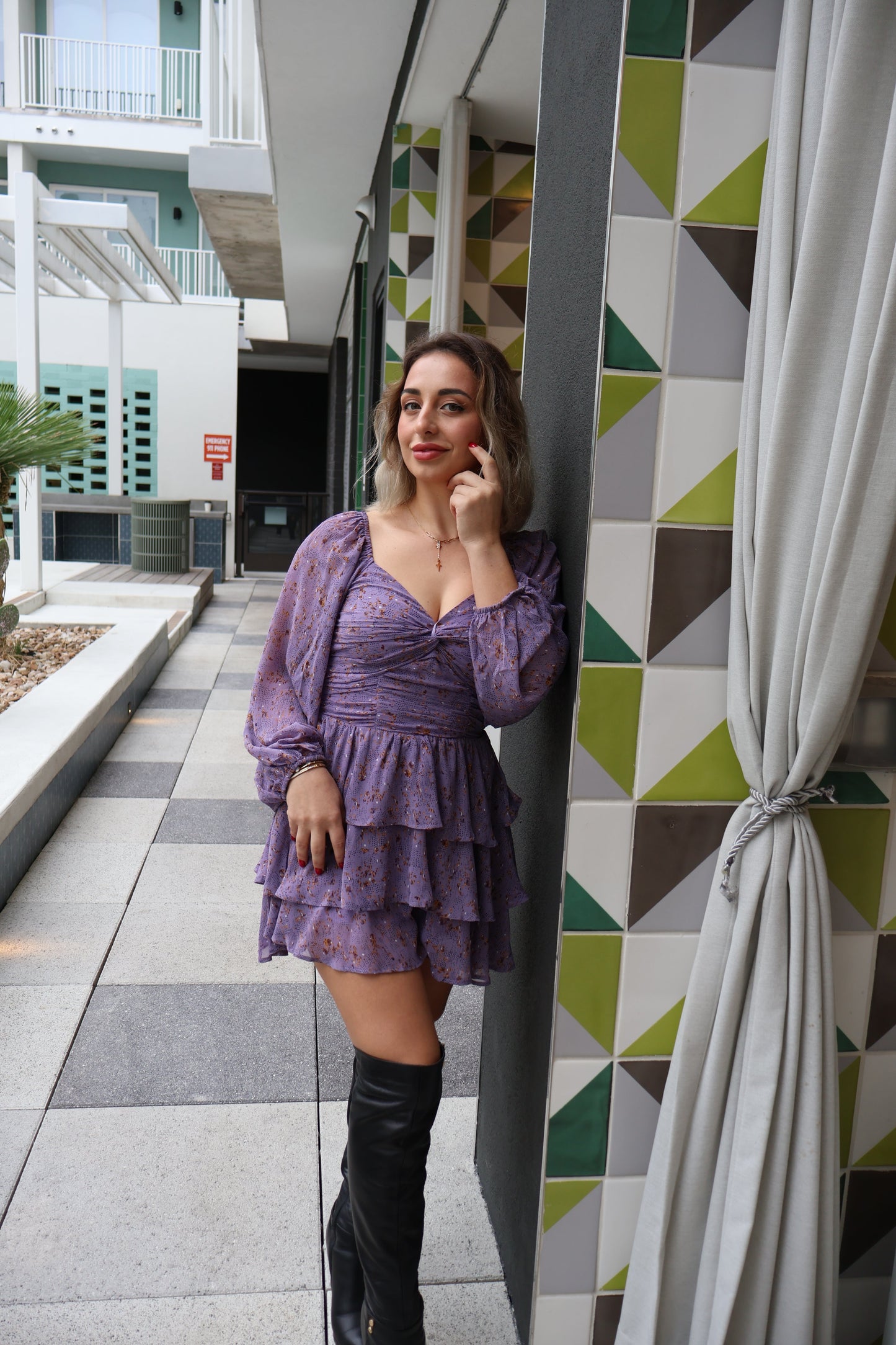 Woman in a purple dress lying on a geometric-patterned ledge with a building in the background