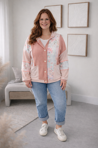 Woman wearing a floral pink jacket and blue jeans indoors.