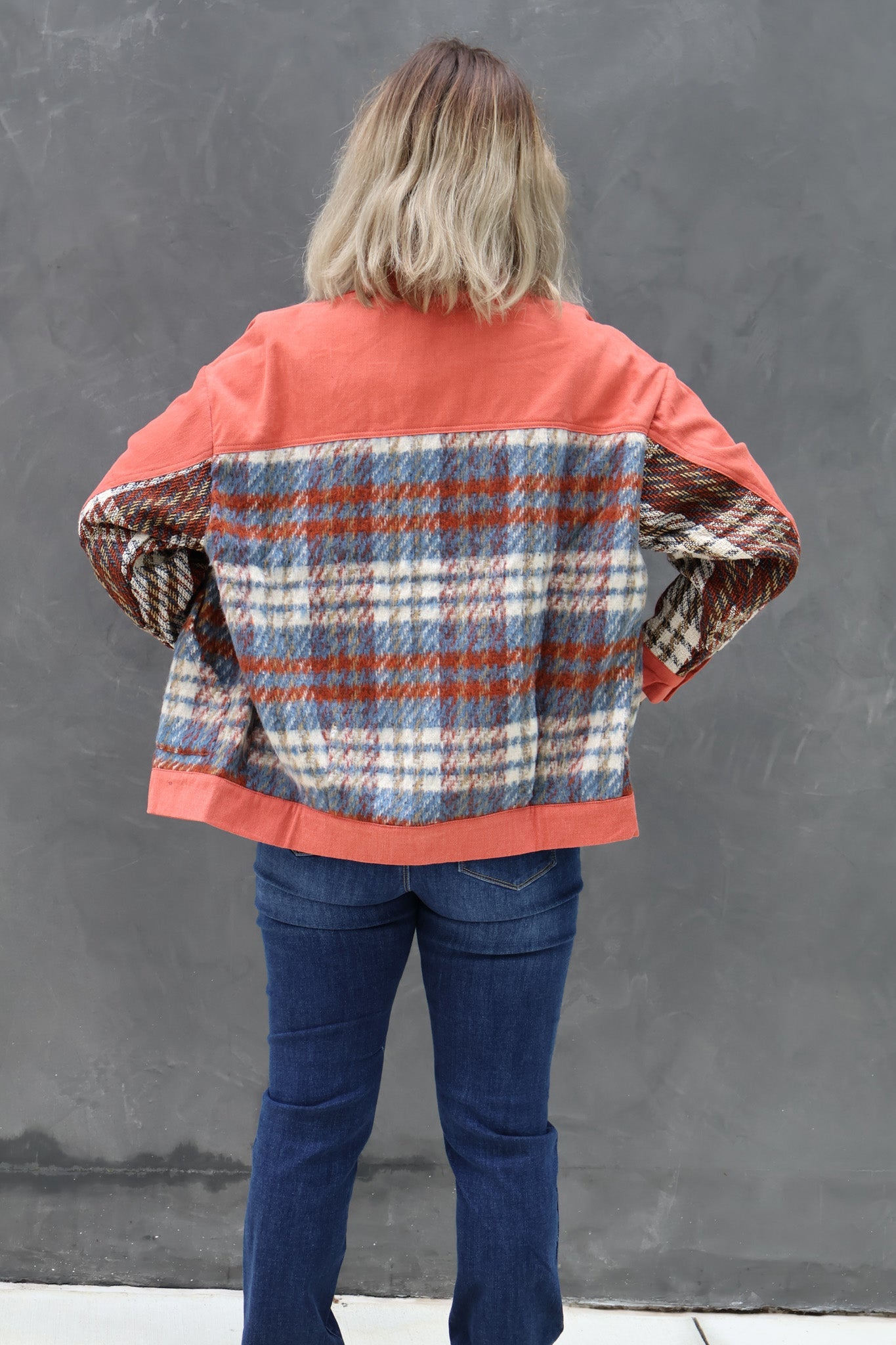 Person wearing a colorful jacket with a plaid pattern on a gray background