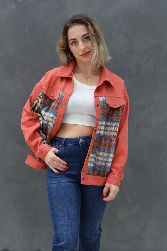 Woman wearing a red jacket with patterned sleeves against a gray background