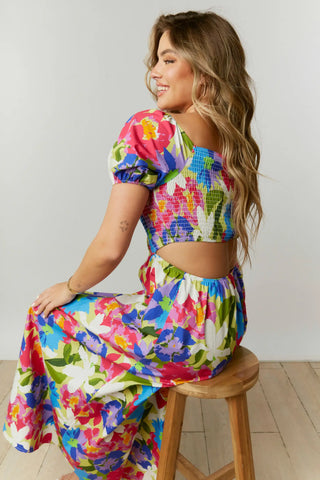 This abstract floral print maxi dress features a cut-out back with a square neckline and short puff sleeves.  The dress is composed with a smocked bodice.