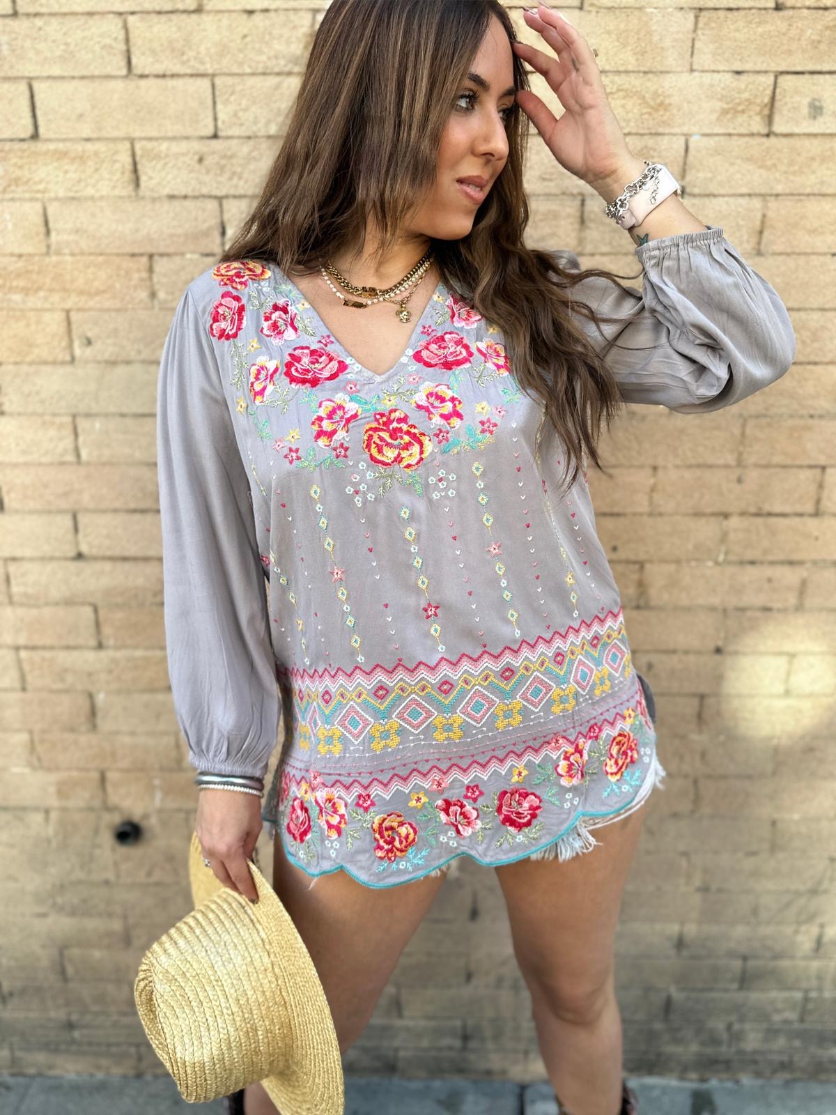  We love the vibe of this gorgeous embroidered blouse. It features a split V-neckline, colorful floral embroidery on a beautiful print, long sleeves  and a relaxed a-line fit.  Pair this up with skinny jeans and booties for a chic look!