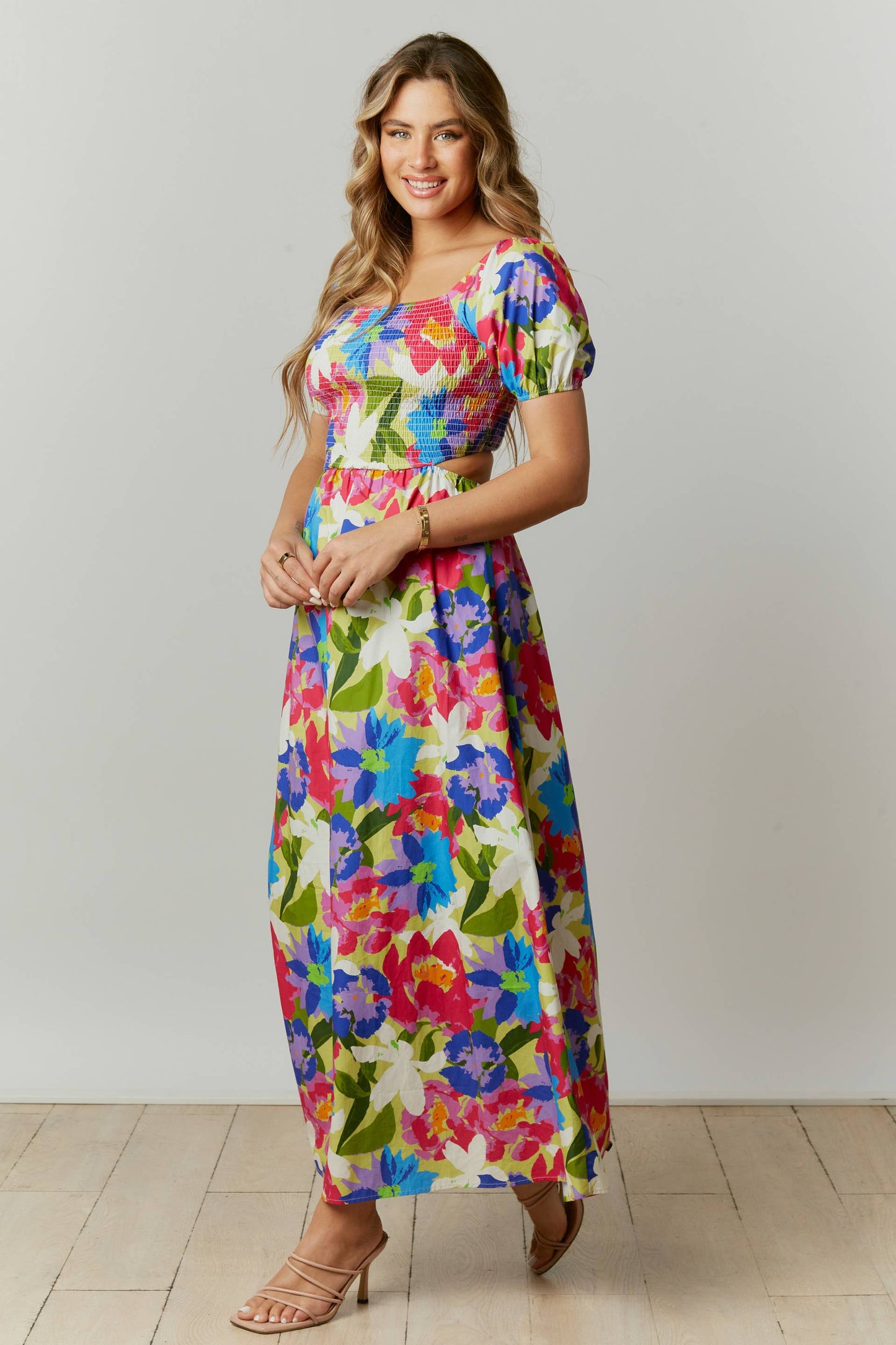 This abstract floral print maxi dress features a cut-out back with a square neckline and short puff sleeves.  The dress is composed with a smocked bodice.