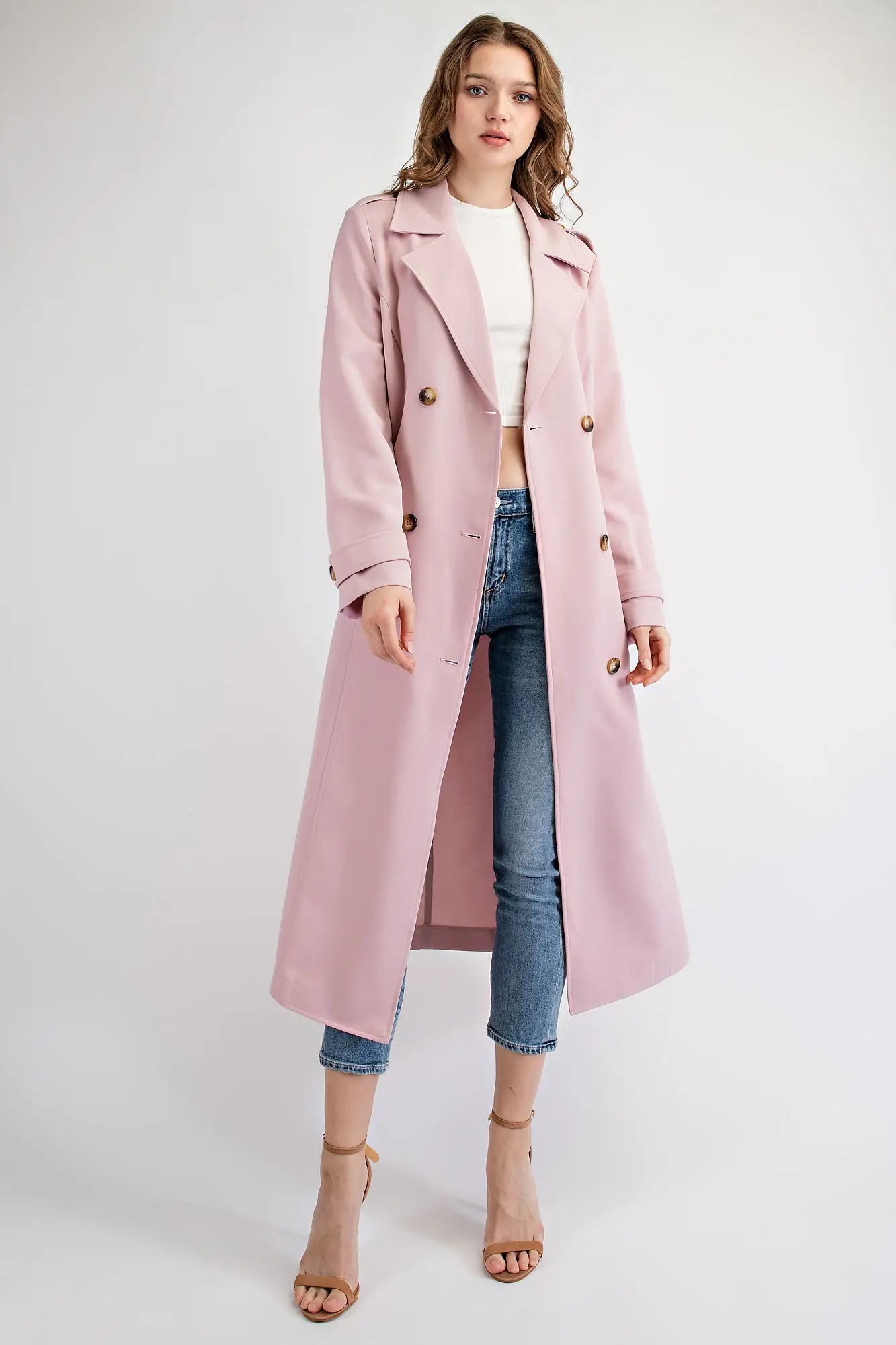 The double-breasted front features large buttons for a traditional look, while the notched lapel and belted waist add to the elegant silhouette. The coat has two side pockets for added convenience and a back vent for ease of movement.